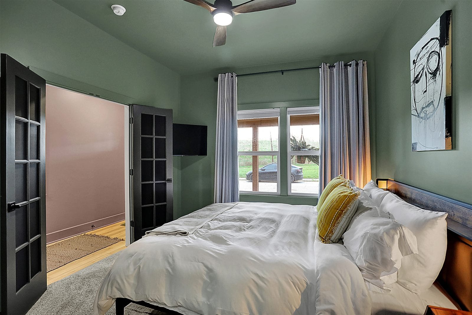 Primary bedroom with king bed, wall TV, and sliding door to private Juliet balcony
