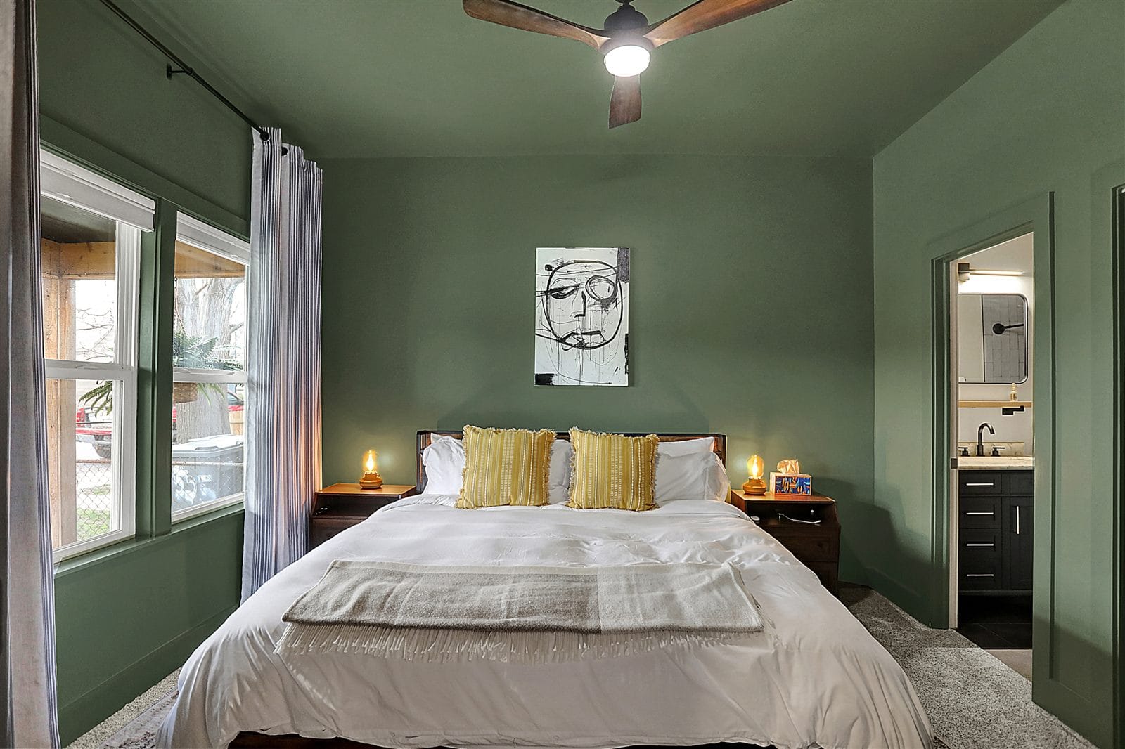Primary bedroom from entry showing king bed, bench, and wall-mounted TV
