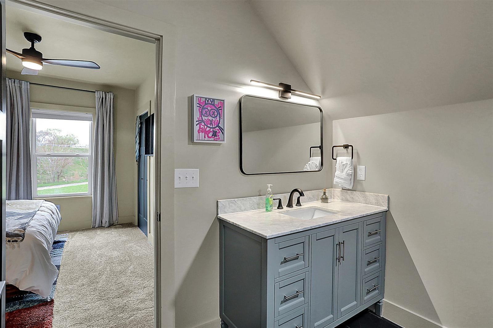 Upstairs hallway vanity with marble top, black fixtures, and arched mirror