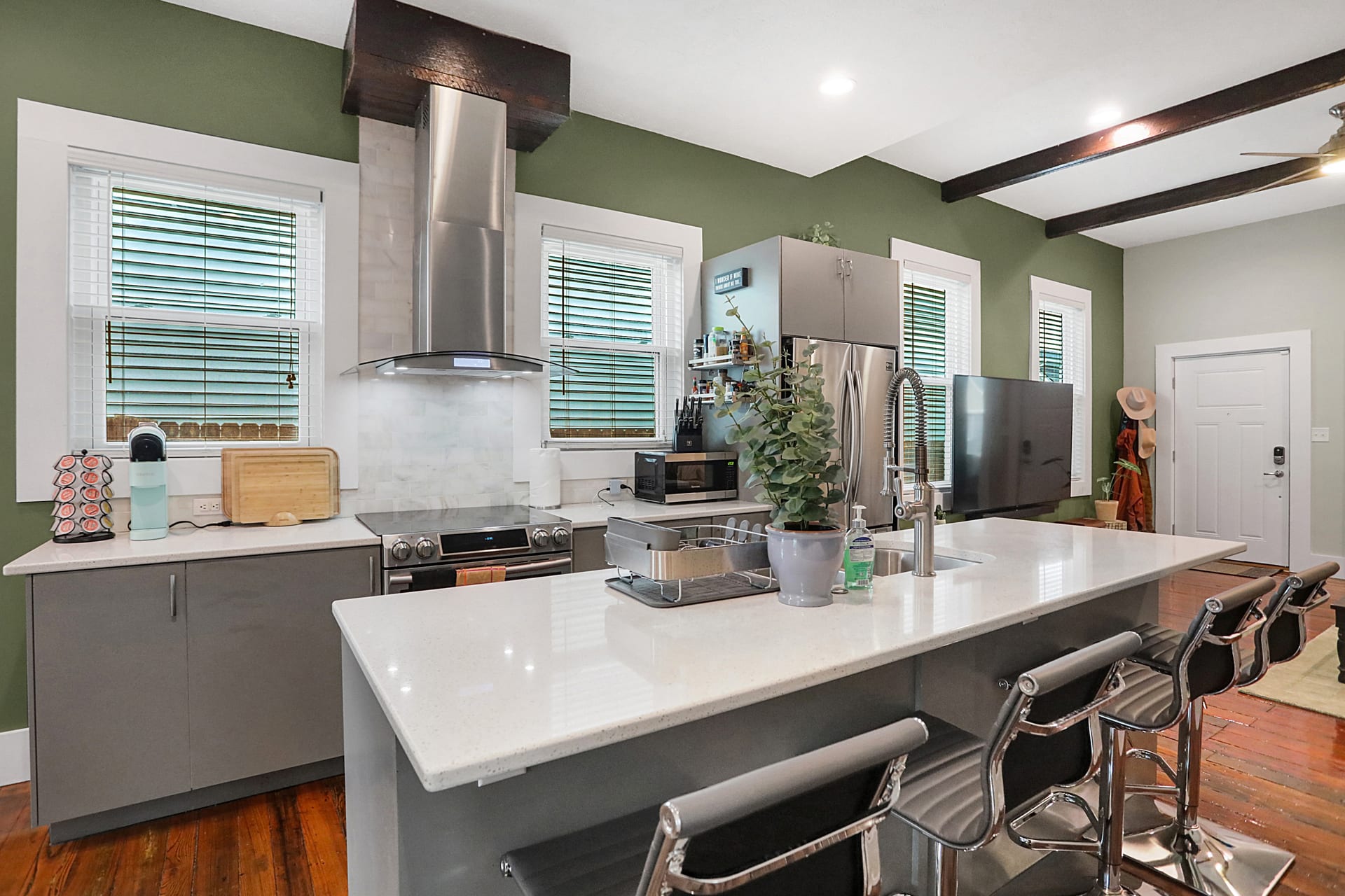 Kitchen island from the cooking side, showing the induction range, marble backsplash, and barn-beam ceiling detail