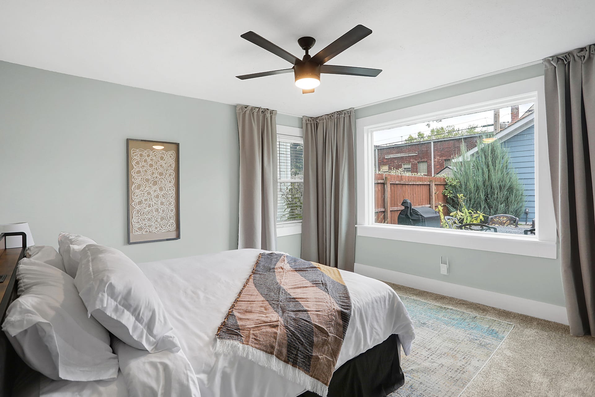 Third king bedroom full view with reading bench, neutral bedding, and a sightline into the kitchen