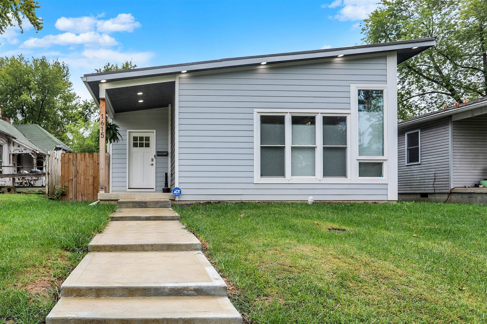 Sage-gray single-story modern home with shed roofline and large picture window